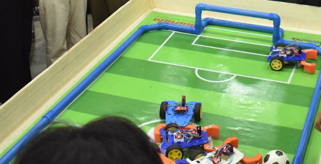 Robots competing on a robot soccer field at Robolution